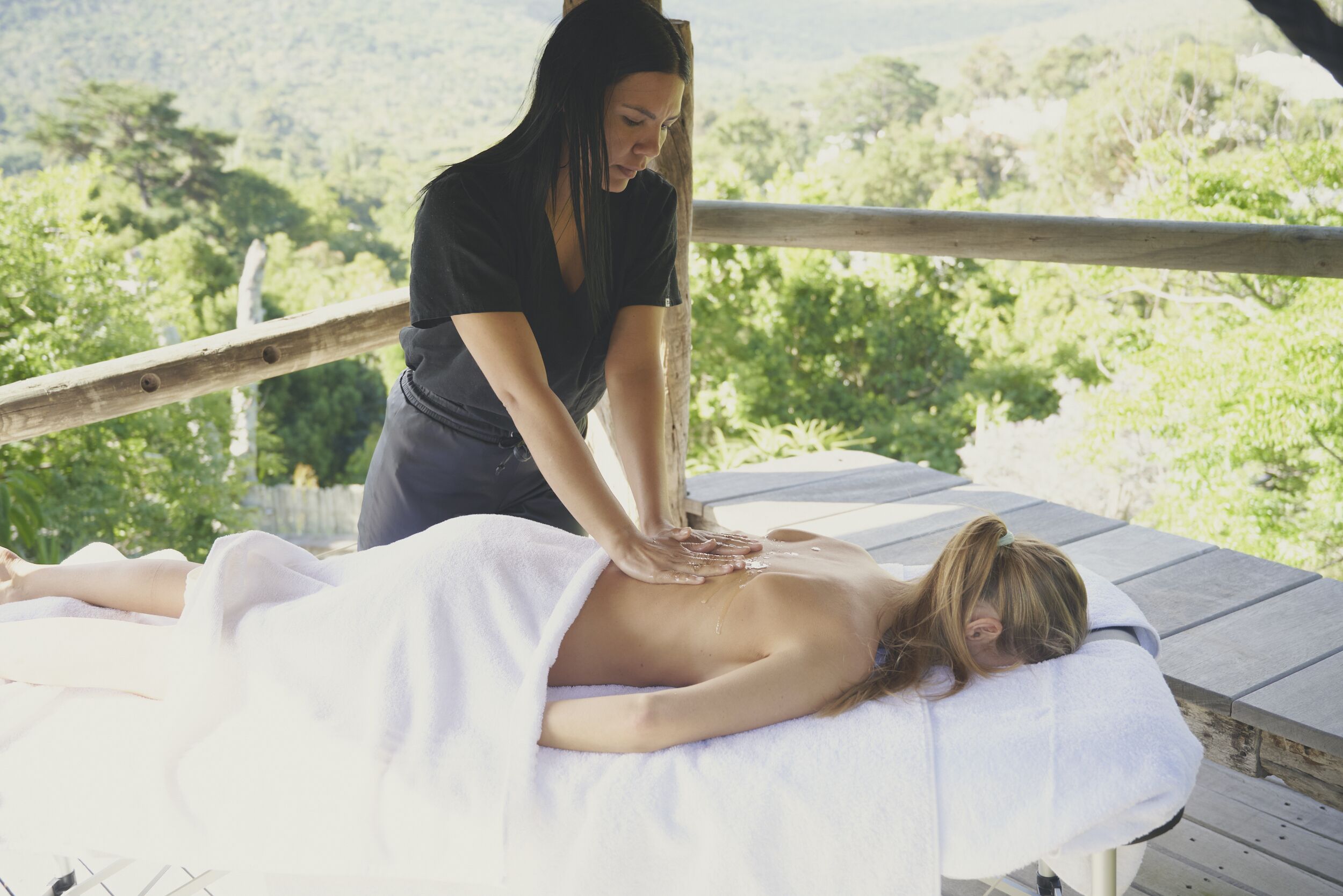 A massage therapy session on a wooden deck with a scenic view.
