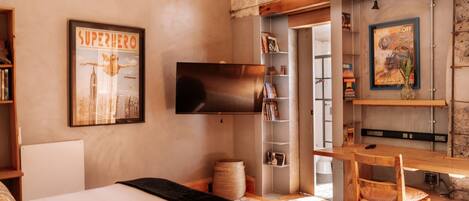 A bedroom with a bed, a desk, a chair, a television, and a bookshelf.