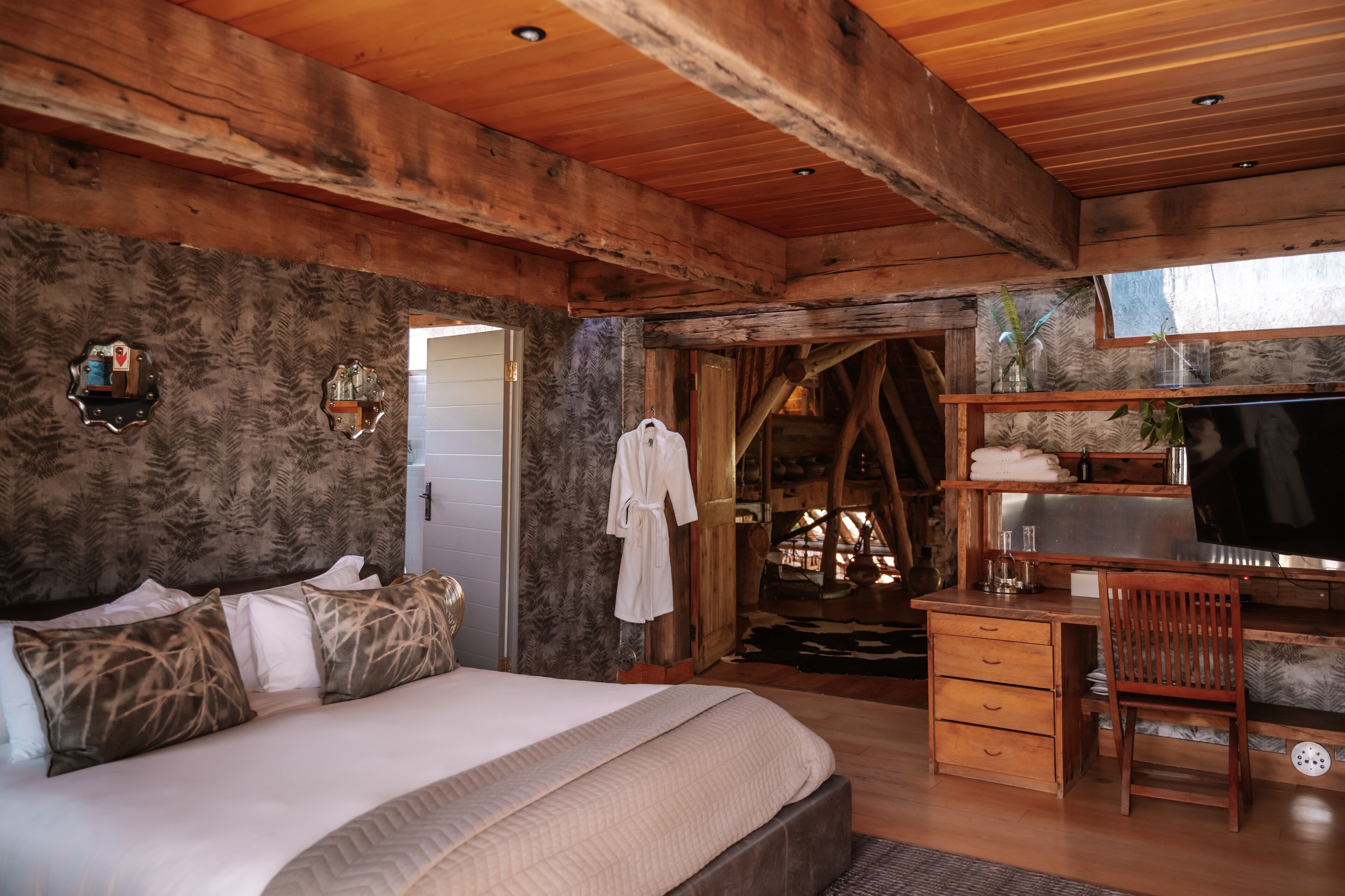 Interior de una cabaña de madera con una cama, un escritorio y un televisor.