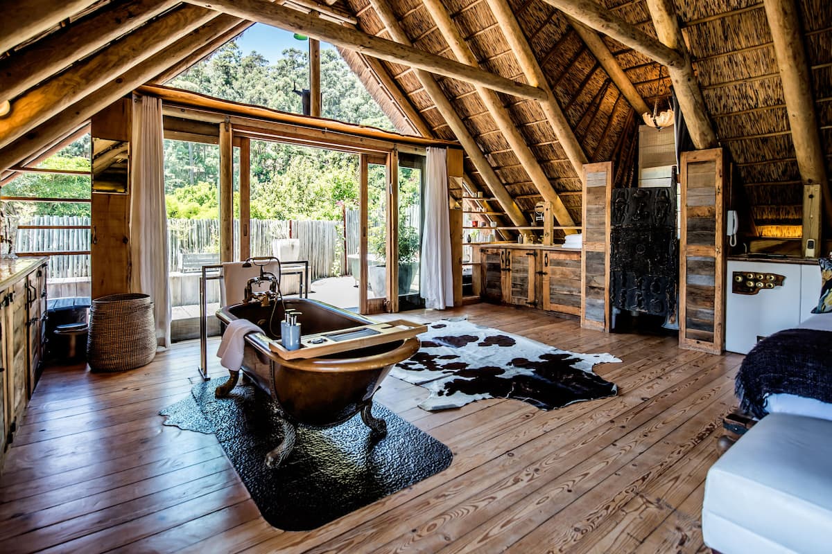 Eine rustikale Holzhütte mit Holzvertäfelung, einer großen Badewanne und einem Kuhfellteppich.