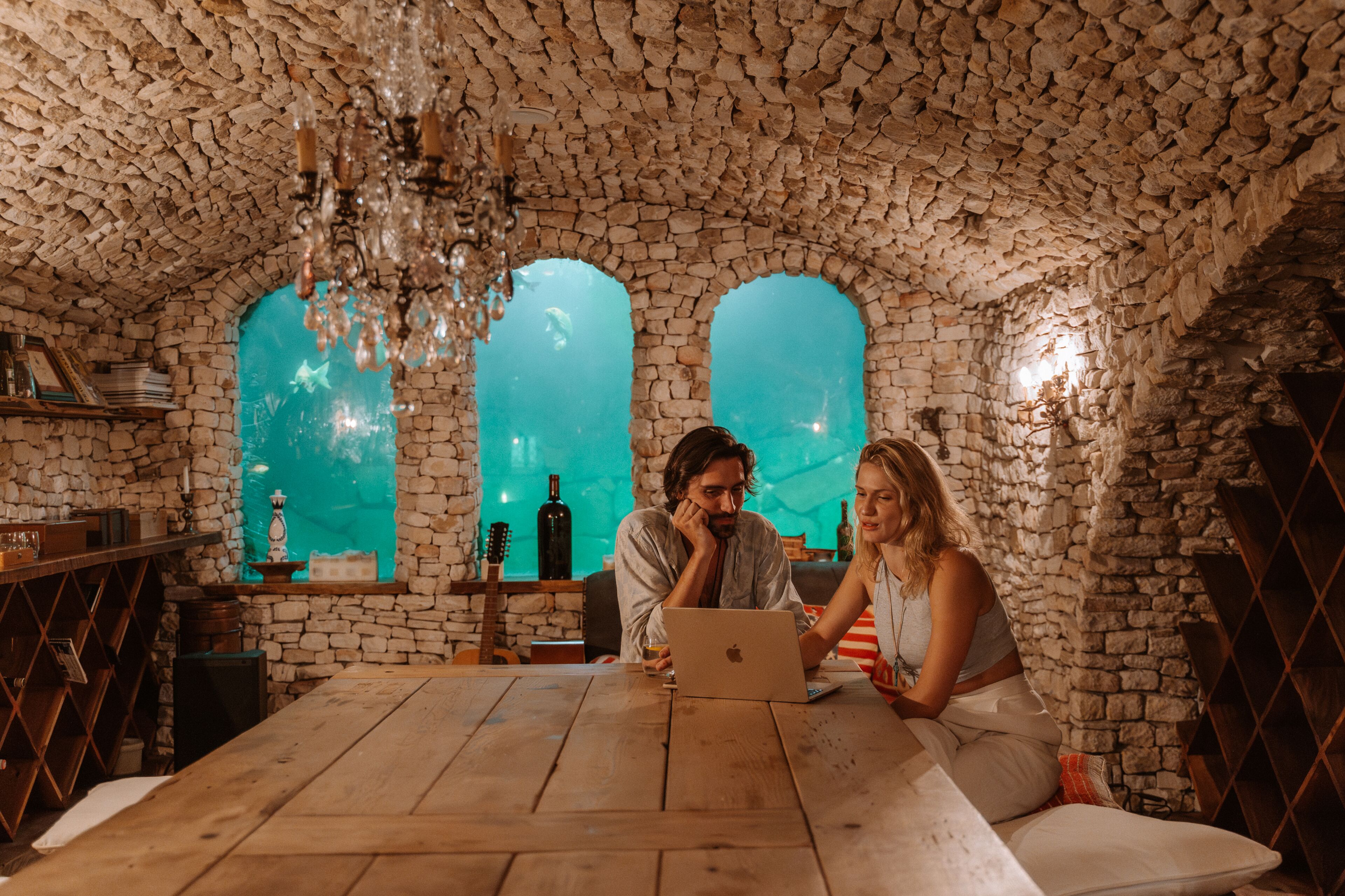 A rustic room with stone walls, a wooden table, and a laptop.