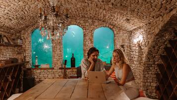 A rustic room with stone walls, a wooden table, and a laptop.