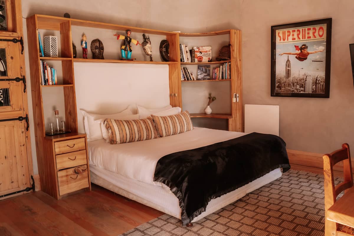 Ein Schlafzimmer mit einem Bett, Nachttischen aus Holz, einem Bücherregal und einem Poster an der Wand.