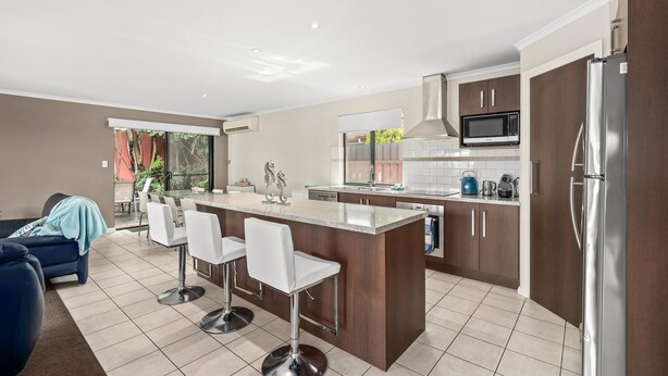 A modern kitchen with a central island, bar stools, and stainless steel appliances. - Seacret Oasis - Aldinga Beach - C21 SouthCoast Holidays (Aldinga Beach)