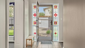 A doorway with a glass door leading to a backyard with a garden and a wooden deck. - Seacret Oasis - Aldinga Beach - C21 SouthCoast Holidays (Aldinga Beach)