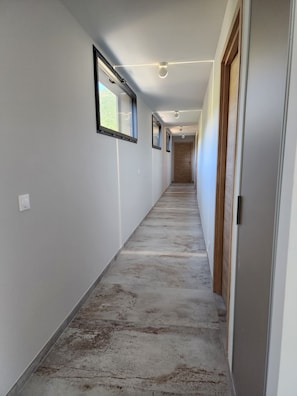 A long, narrow hallway with white walls, wooden doors, and a concrete floor. - Villa Aria Terra — Pinarello, sea view, heated pool 29°C, sea-view sauna (Conca)
