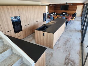 Une cuisine moderne avec des meubles en bois, un îlot central et un coin repas comprenant des chaises et une table.