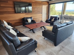 Una sala de estar moderna con sofás de cuero, una mesa de centro de madera y un televisor grande montado en una pared de madera.