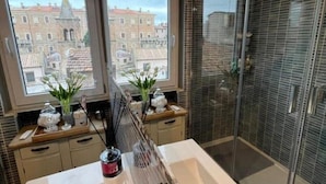 A bathroom with a bathtub, a shower, and a window with a view of buildings.