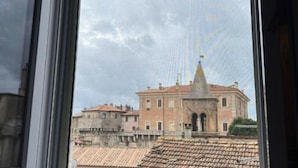 A view through a window of a building with a tiled roof and a prominent tower.