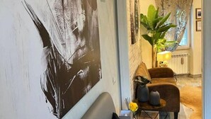 A modern living room with a large abstract painting, a sofa, a coffee table, and a potted plant.