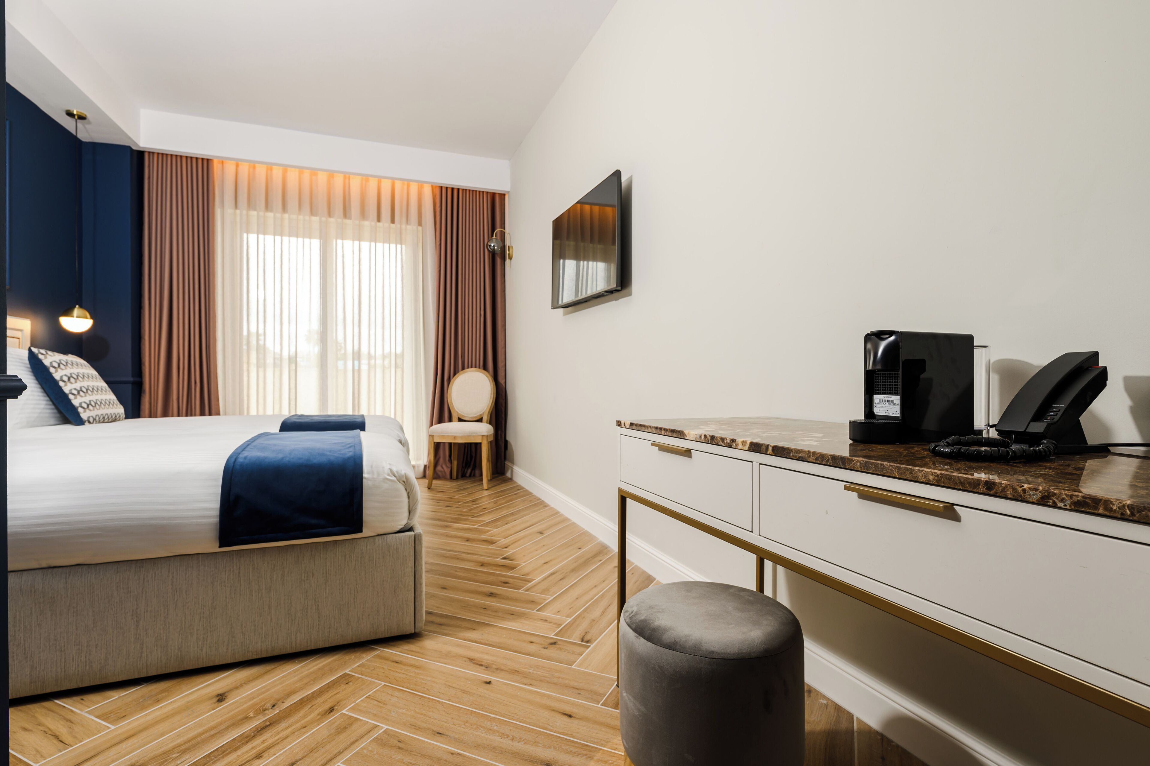 Ett hotellrum med en säng, ett skrivbord, en stol, en kaffebryggare och en tv.