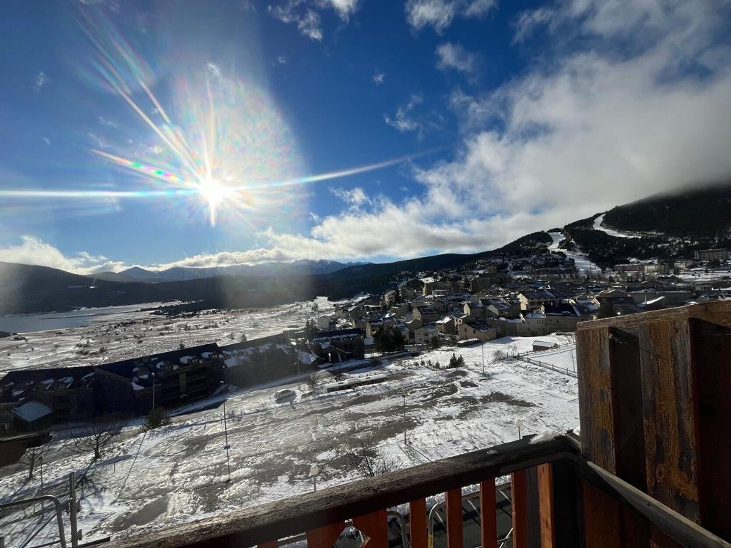 A snowy landscape with a town and mountains in the background.