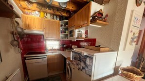 A compact kitchen with wooden cabinets, a washing machine, and a refrigerator. - 3-Room Duplex - Lake and Mountain View - Parking Included (Les Angles)