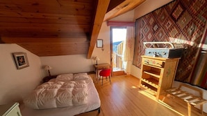 A bedroom with a bed, a wooden dresser, a red chair, and a window with curtains. - 3-Room Duplex - Lake and Mountain View - Parking Included (Les Angles)