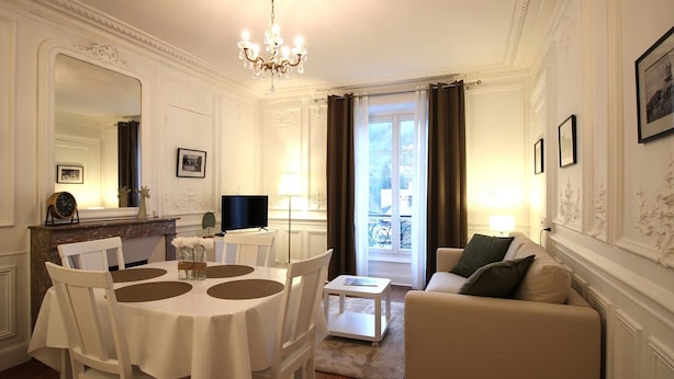 Un salon bien éclairé comprenant un coin repas, un canapé et un téléviseur.