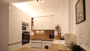 Une cuisine compacte dotée d’un plan de travail en bois, d’un four encastré, d’un four à micro-ondes et d’un lave-linge.
