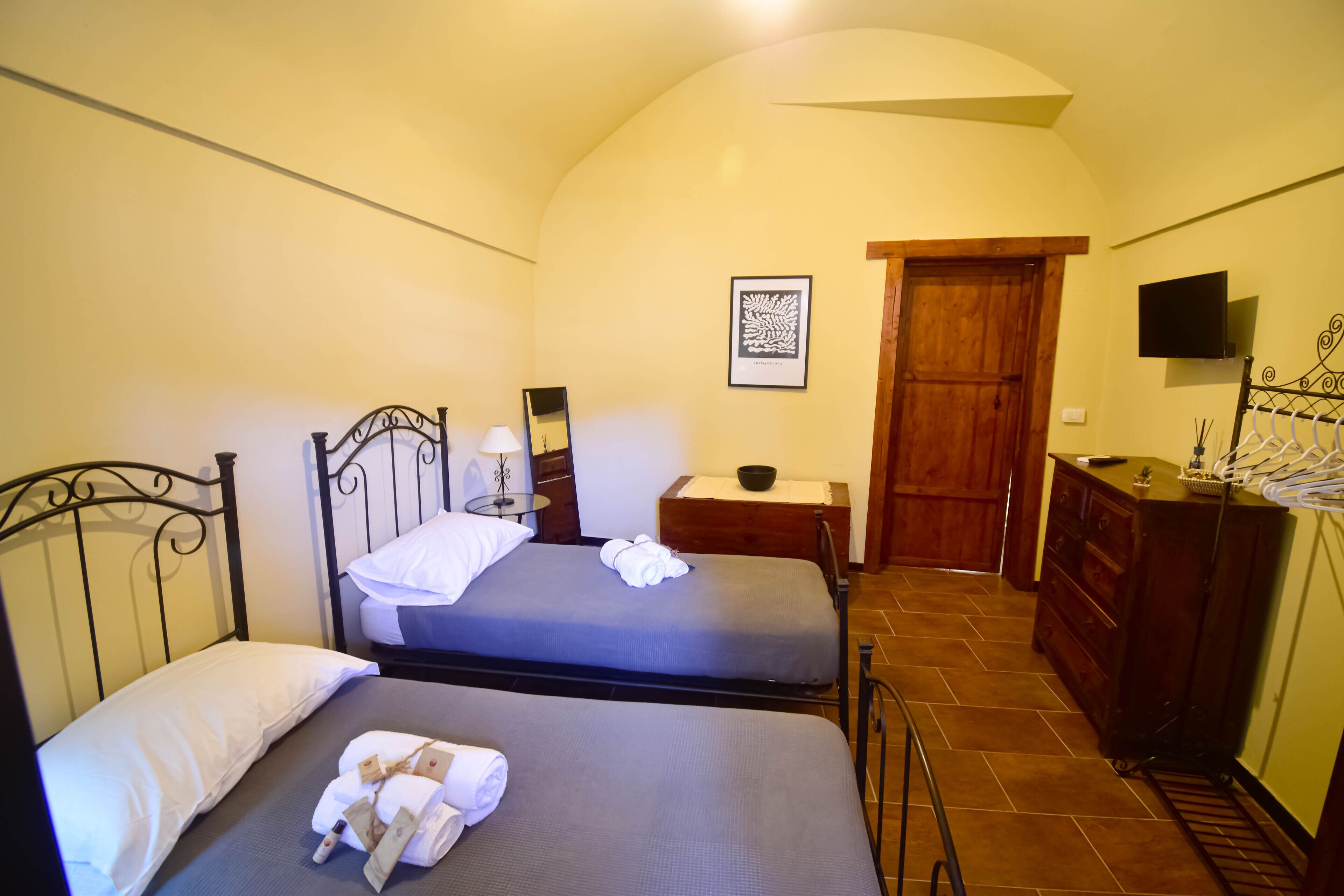 Camera da letto con due letti, una porta in legno, un comò e un quadro appeso al muro.