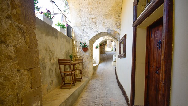 A narrow cobblestone alleyway with stone walls, wooden benches, and a wooden door. - Domum in petra, the house in the rock. A short walk from the historic center of Modica (Modica)
