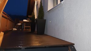 A covered outdoor area with a wooden deck, a small table with chairs, and potted plants. - Apartment "Waldblick" with Balcony & Wi-Fi (Westerheim)