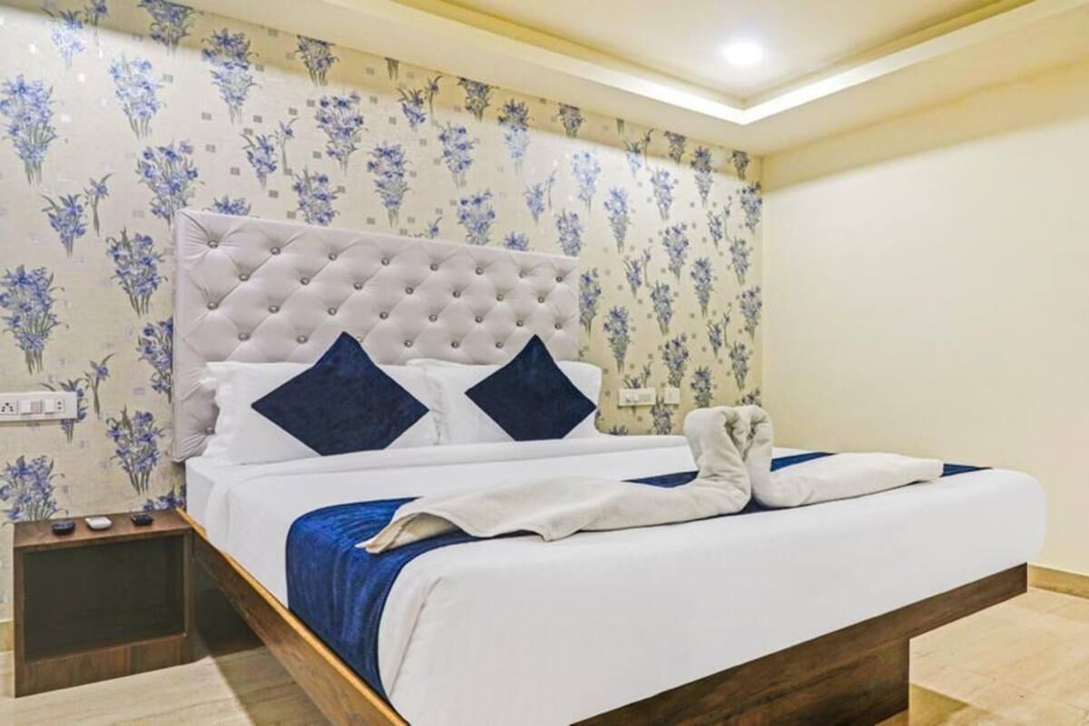 A neatly made bed with a tufted headboard, two pillows, and a folded towel.