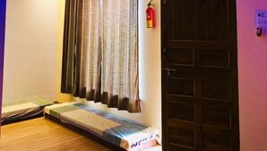A room with a bed, a door, and a ceiling with recessed lighting. - Kisan Eco Farm (Kalyan)