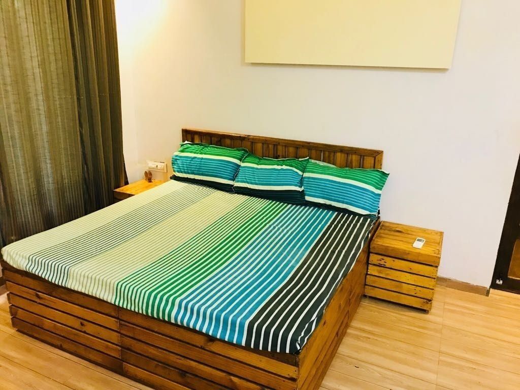 A bed with a striped bedspread, wooden headboard, and matching pillows.