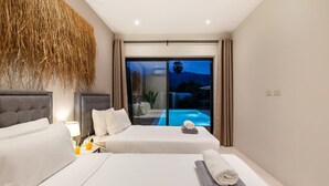 A modern hotel room with two beds, a large window with a view of a swimming pool, and a decorative wall hanging. - Sereniwood 1 - 2BR Pool Villa (Koh Samui)