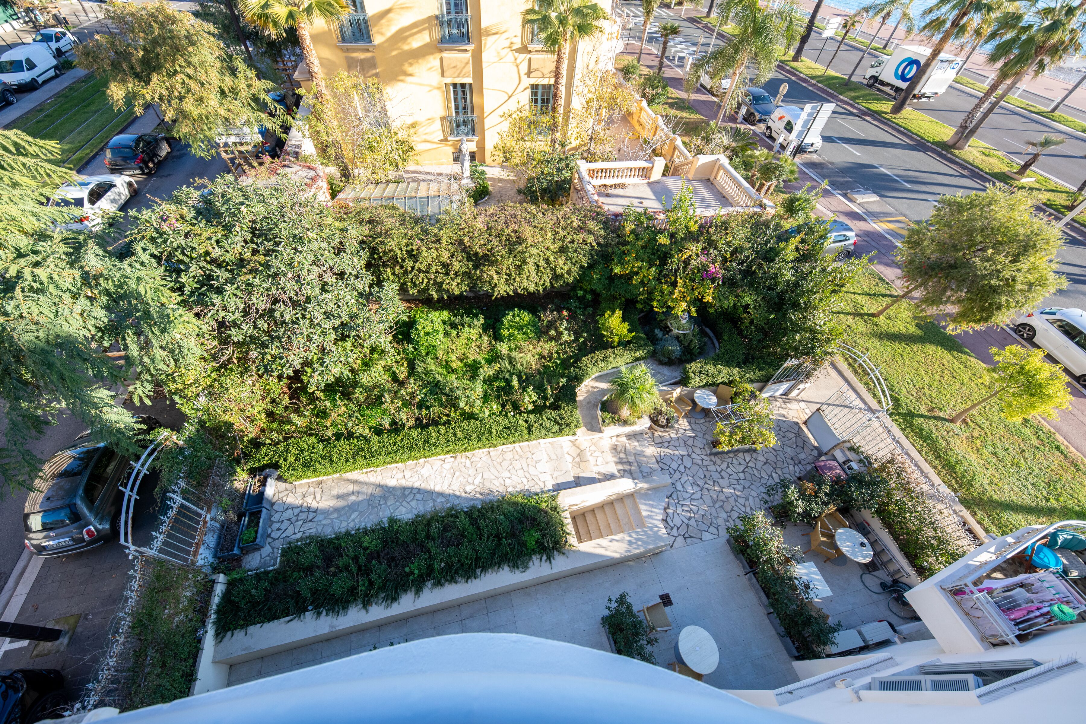 Vista aérea de un patio de hotel con piscina, mobiliario exterior y zona de estacionamiento.