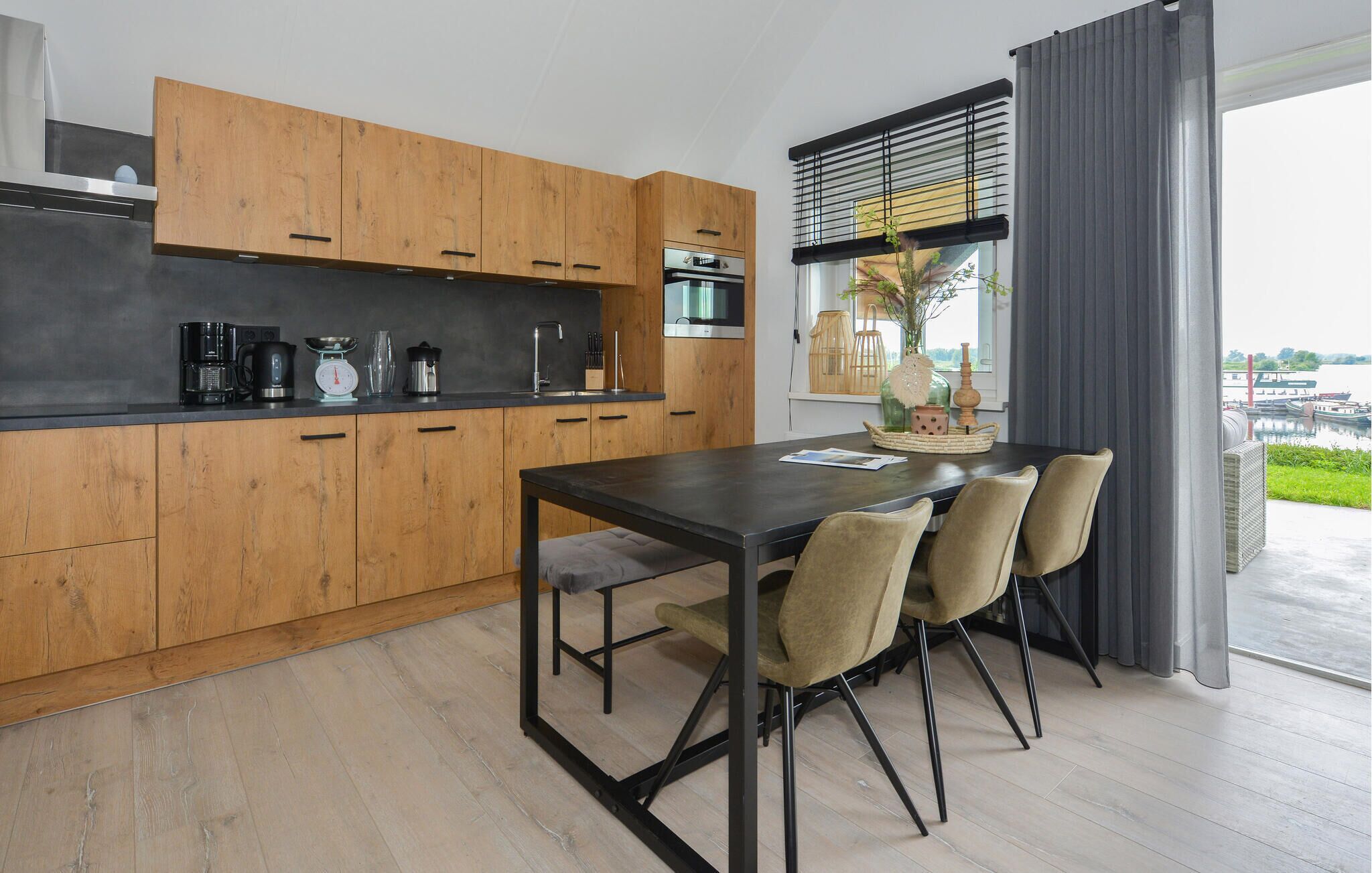 A modern kitchen with wooden cabinets, a black countertop, and a dining area with a table and chairs.