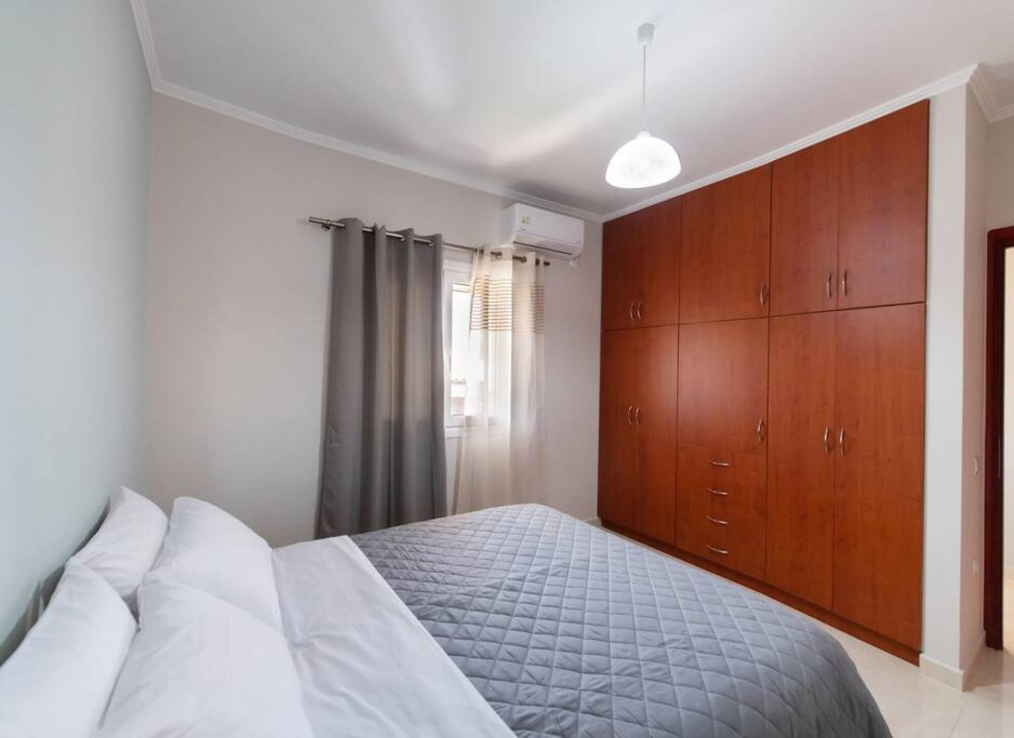 A bedroom with a bed, a wardrobe, and a ceiling light.