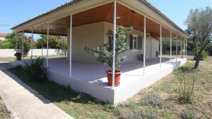 A covered outdoor area with a concrete floor, potted plants, and a small tree. - Olga Home Agios Ioannis Lefkada - Lefkada BnB (Lefkada)