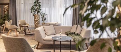 A modern living room with a sofa, armchairs, a coffee table, and a potted plant.