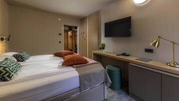 Una habitación de hotel con una cama, un escritorio, un televisor y una lámpara.