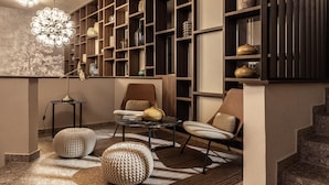 Una sala de estar moderna con sofá, sillones, una mesita de centro y una estantería llena de objetos decorativos.