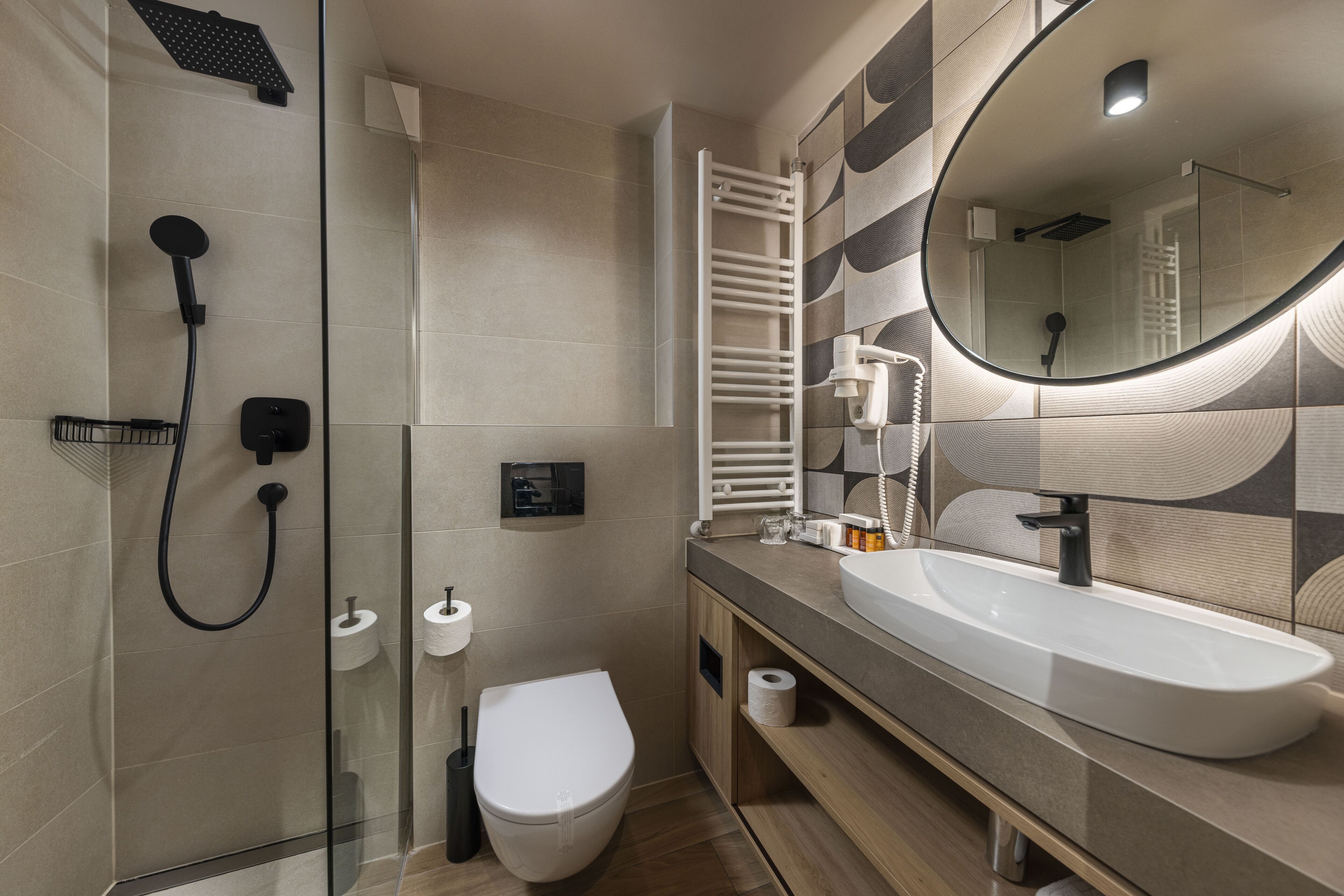 A modern bathroom with a glass-enclosed shower, a white toilet, a sink with a mirror, and a towel rack.