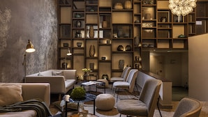 Un interior moderno con una zona de estar, una pared decorativa con estantes y una lámpara original.