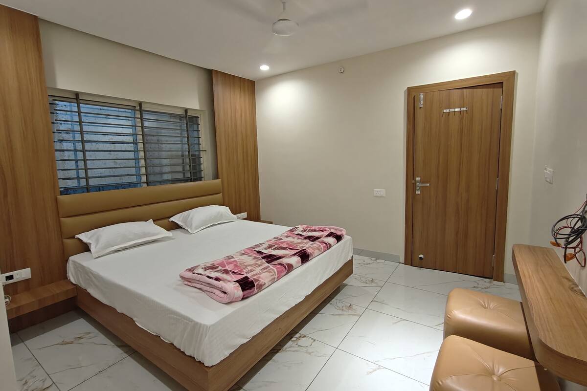 Un dormitorio con cama, ventana con persianas, puerta de madera y escritorio con silla.