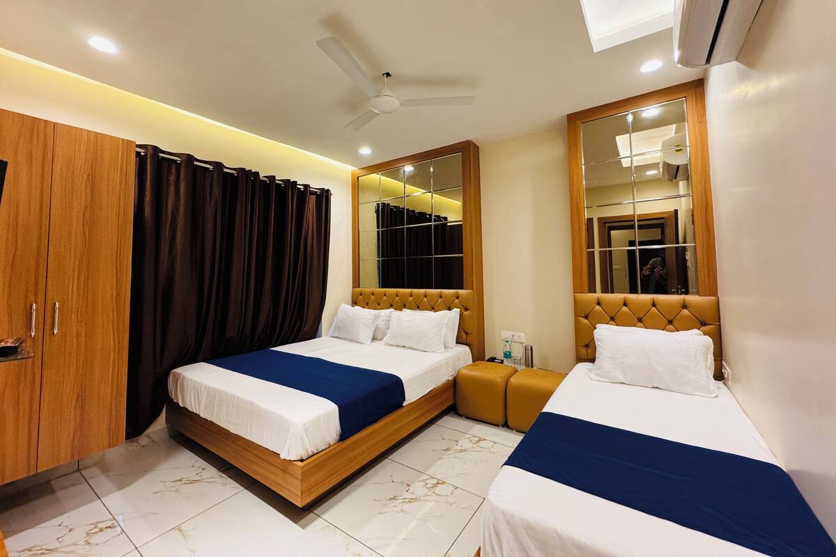 Habitación de hotel con dos camas, un armario, un espejo y un equipo de aire acondicionado.