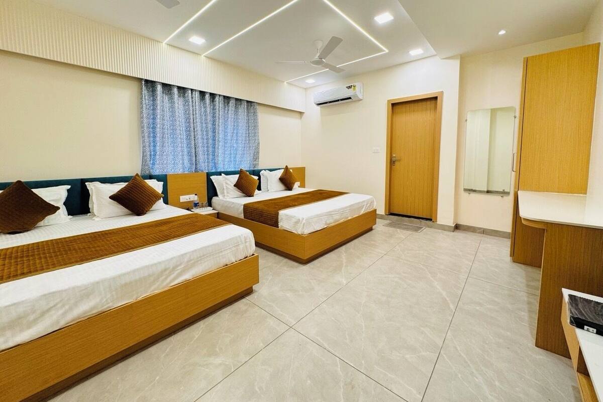 Habitación de hotel con dos camas, ventilador de techo, aire acondicionado y un armario de madera.