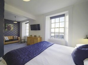 A bedroom with a large bed, a sofa, a TV, and a window with a view. - The Lord Nelson Hotel  (Milford Haven)