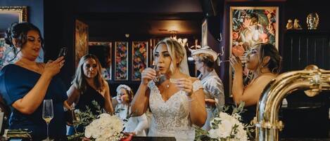 A bar area with a counter, glasses, and flowers.