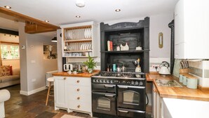 A modern kitchen with a built-in stove, white cabinetry, and a wooden countertop. - The Old Bakehouse (Leominster)