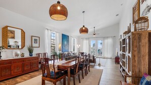 A spacious dining area with a long wooden table and chairs, a wooden buffet, and a bookshelf. - Tranquil Tides, an exquisite beach home on Hill St with beach access directly across street! (New Smyrna Beach)