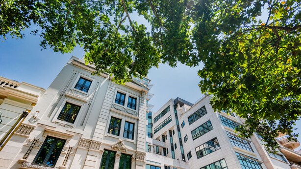 Un immeuble à plusieurs étages, présentant un mélange de styles architecturaux classiques et modernes, avec des balcons et de grandes fenêtres.