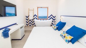 Un dormitorio moderno con una cama grande, un escritorio y vistas al mar a través de una ventana.