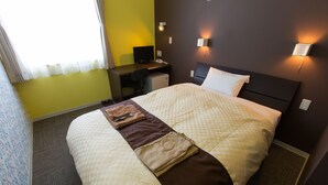A hotel room with a bed, a desk, a chair, and a small refrigerator. - OGAL INN (Shiwa)
