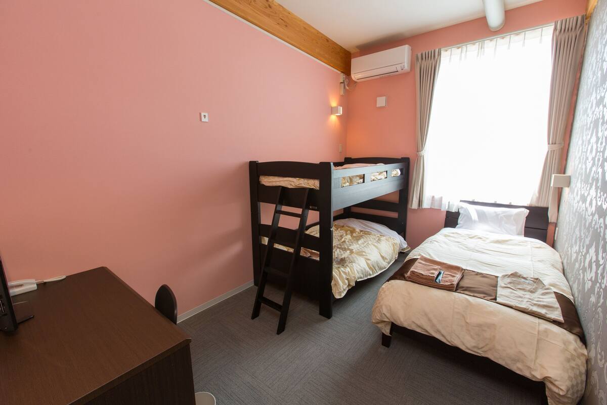 A bedroom with a bunk bed, a desk, and a chair.