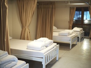 A hotel room with three single beds, each with neatly folded white towels. - Krung Tone Hostel (Bangkok)