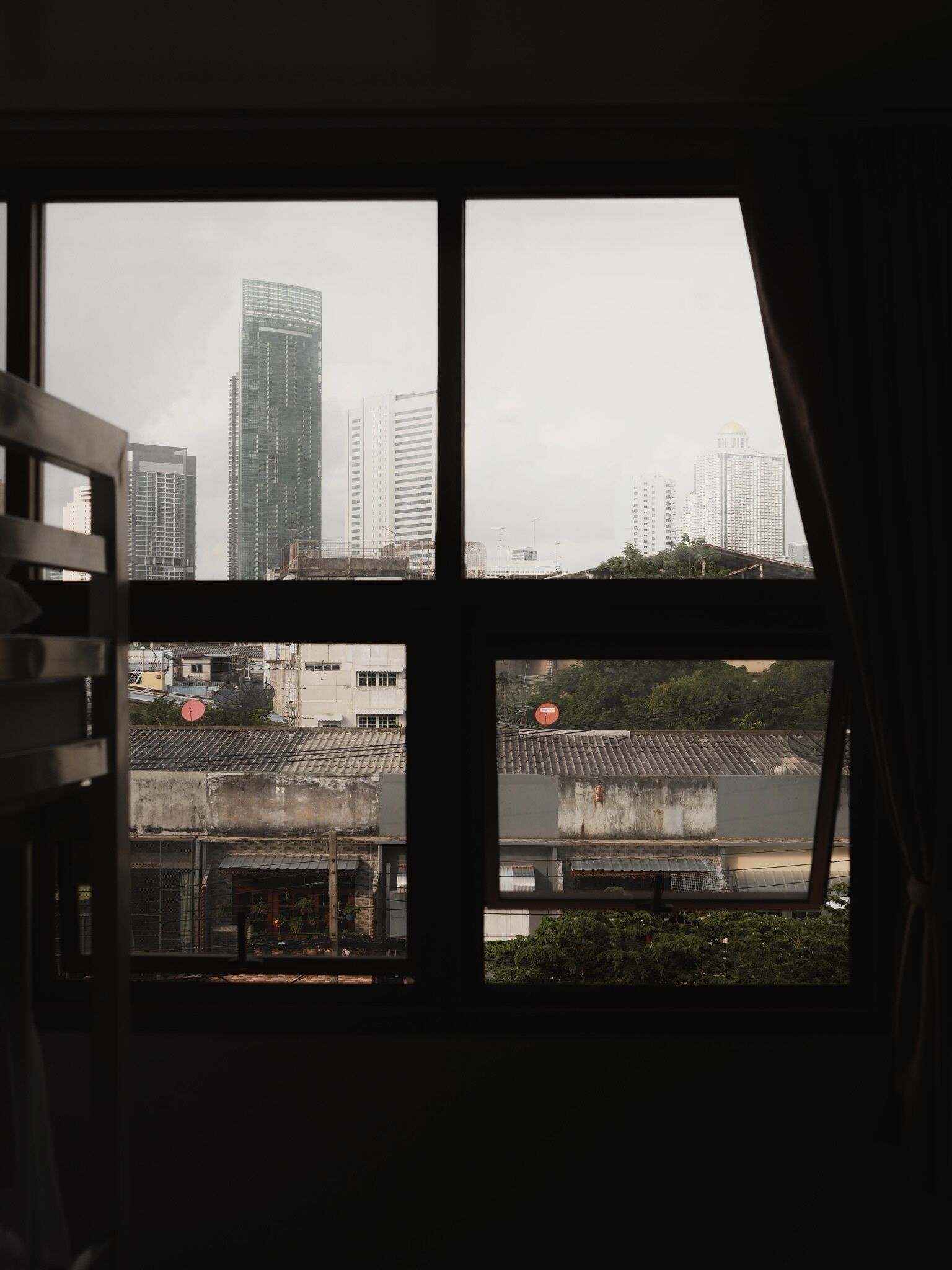 A view through a window with a cityscape, including modern high-rise buildings and traditional architecture.